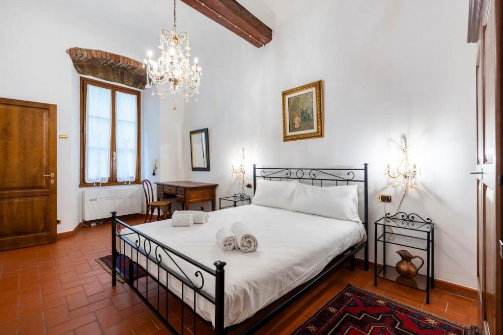 una camera da letto con un letto con lenzuola bianche e un lampadario a braccio di 2BDR - Duomo & Uffizi - Chic Residence of the Cerchi by Hôtea a Firenze