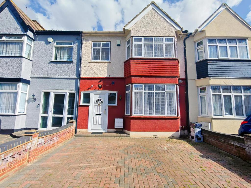 a red and white house with a brick driveway at Shelters En-suite Entire House in Seven Kings