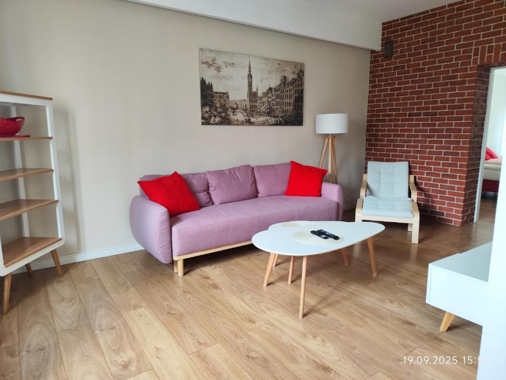a living room with a purple couch and a table at Grand Tourist Simple Rest Apartments in Gdańsk
