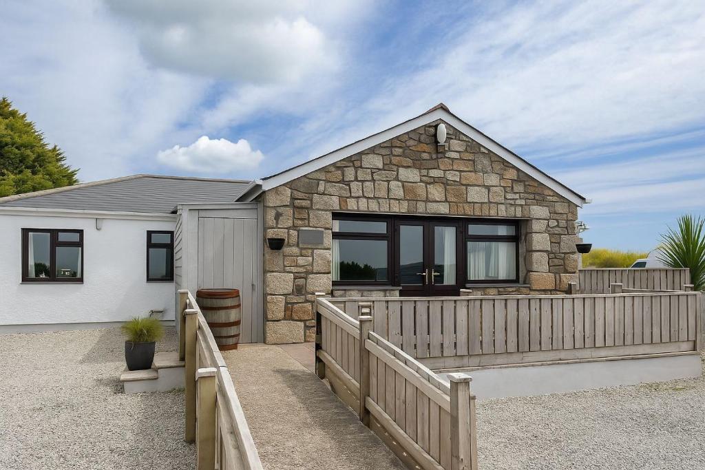 una casa con una valla de madera delante de ella en Wheal Francis - Hot Tub - Accessible Bungalow - Free Wi-Fi - Parking, en Helston