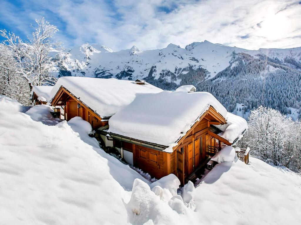 a cabin covered in snow in the mountains at Chalet 4****, 12 personnes, spa panoramique - FR-1-304-302 in La Clusaz