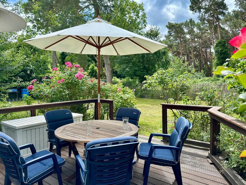 a wooden table with chairs and an umbrella on a deck at Haus am Meer in Thiessow