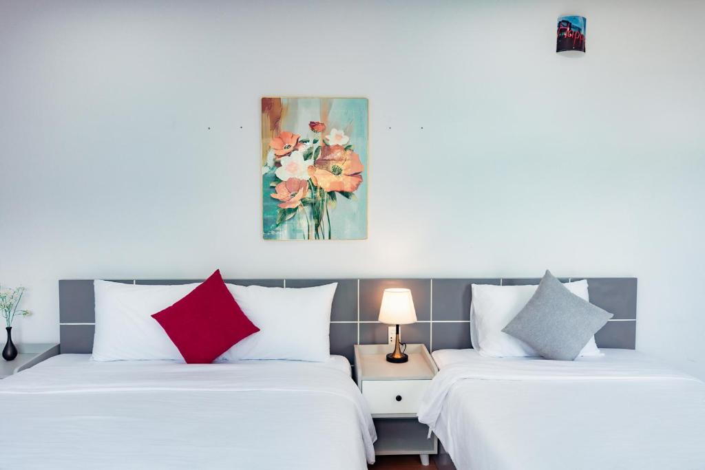 two beds in a hotel room with red and white pillows at Sunshine Hotel in Buon Ma Thuot