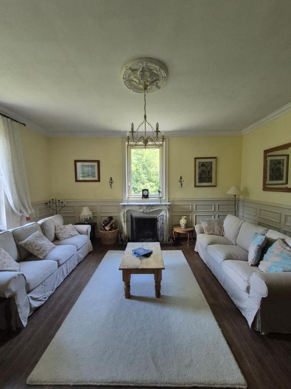 a living room with white couches and a fireplace at Chateau Le Vieil Etang in Saint-Sauveur-le-Vicomte