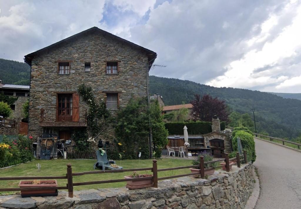 una casa de piedra con una valla delante de una carretera en Gran Casa de Montana, en Fornells de la Muntanya