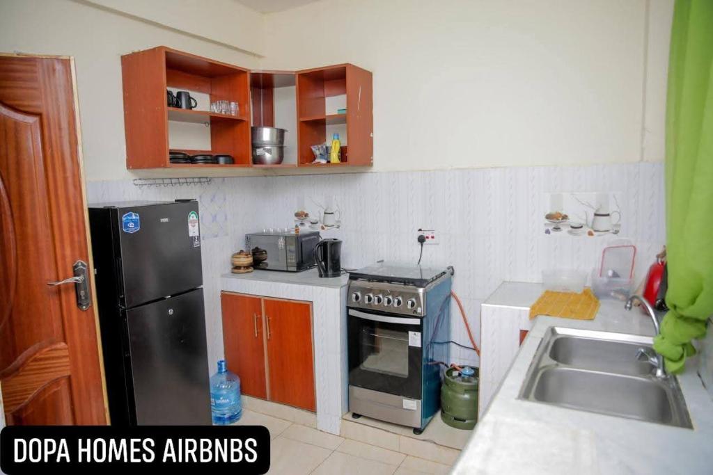 a kitchen with a black refrigerator and a sink at Dopa Homes Airbnbs in Meru