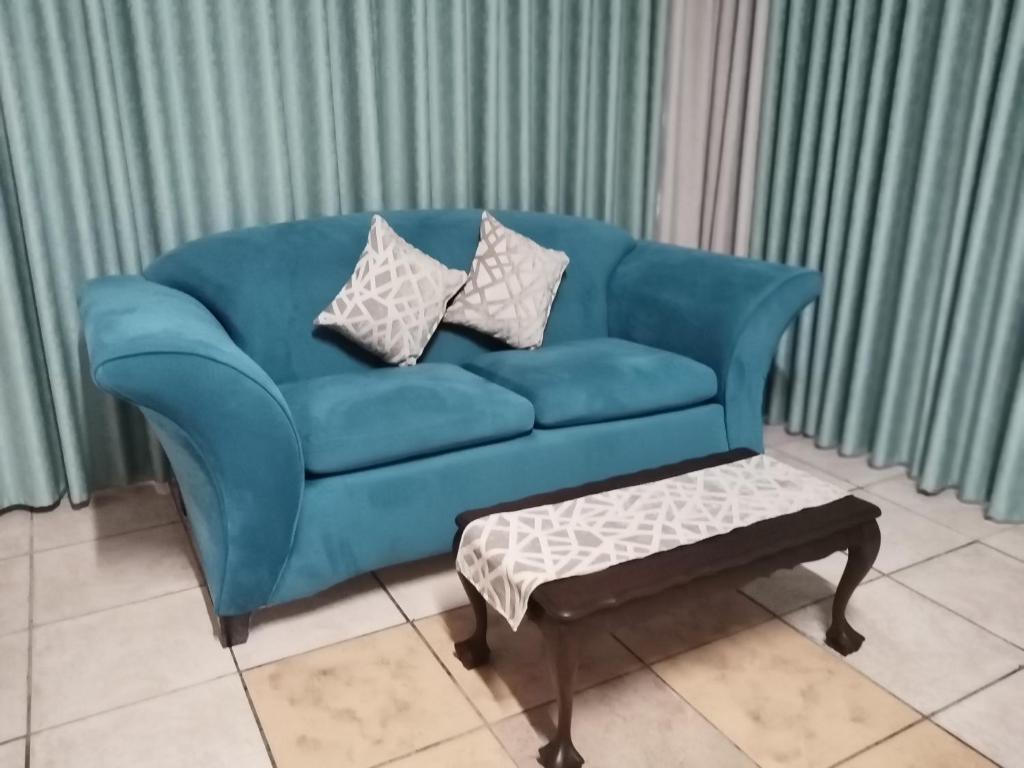 un divano blu in soggiorno con tavolino di Capital Park entire rental unit a Pretoria