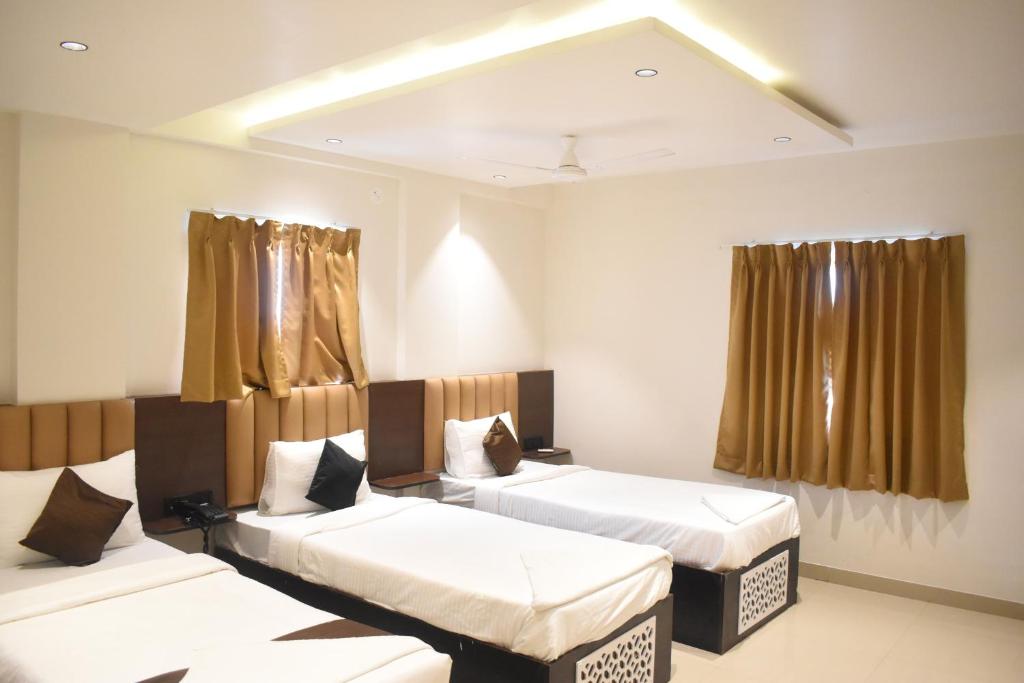 a room with three beds and curtains in it at Lotus Excutive in Pune