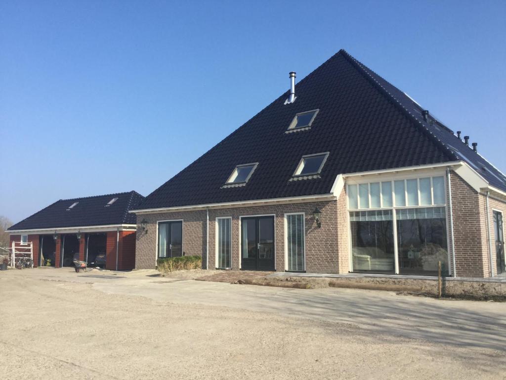 a large house with a black roof at Boerderij de Waard in Anna Paulowna