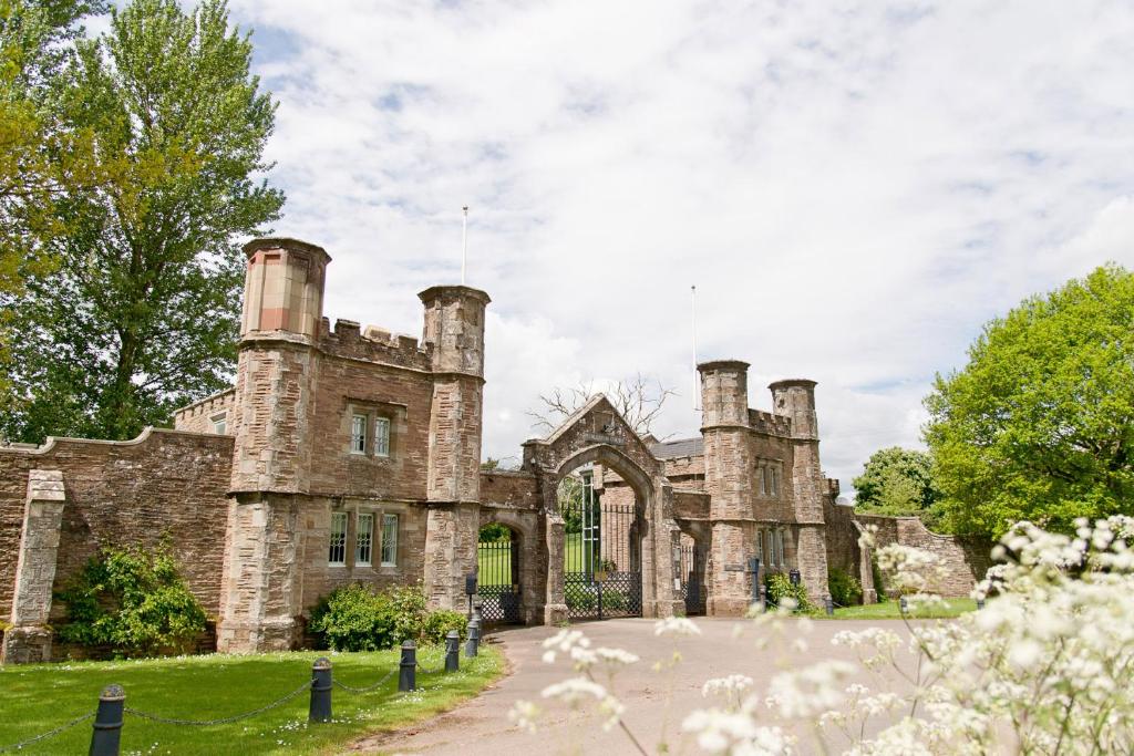an old stone house with three chimneys on the front at The Gatehouse at Pudleston Court in Hatfield