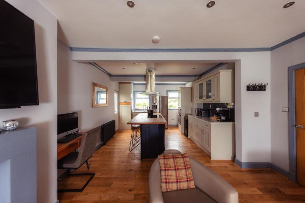 a living room with a couch and a kitchen at Hamara Luxury Portree Cottage with Hot Tub! in Portree