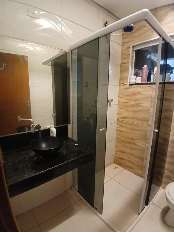 Un baño con lavabo y ducha de cristal. en Casa aconchegante, en Salto