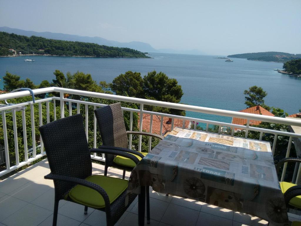 einen Tisch und Stühle auf einem Balkon mit Blick auf das Wasser in der Unterkunft Apartments Vukas in Lumbarda