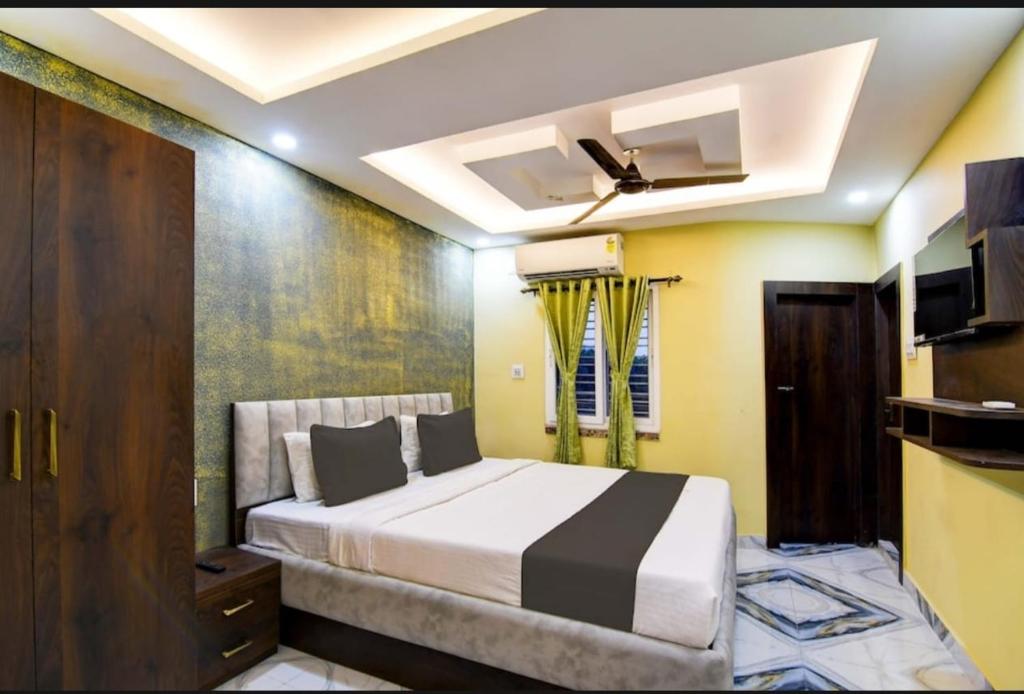 a bedroom with a bed and a ceiling fan at The Crown Inn Madhyamgram in kolkata