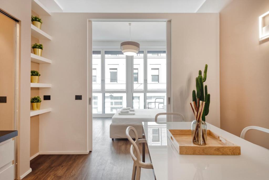 Duomo Apartments B Home - Panoramic Two Bedrooms Apt في ميلانو: مطبخ وغرفة معيشة مع طاولة وسرير