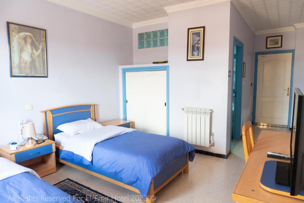 a bedroom with a bed and a desk and a tv at Hotel El Emir Djelfa in Djelfa