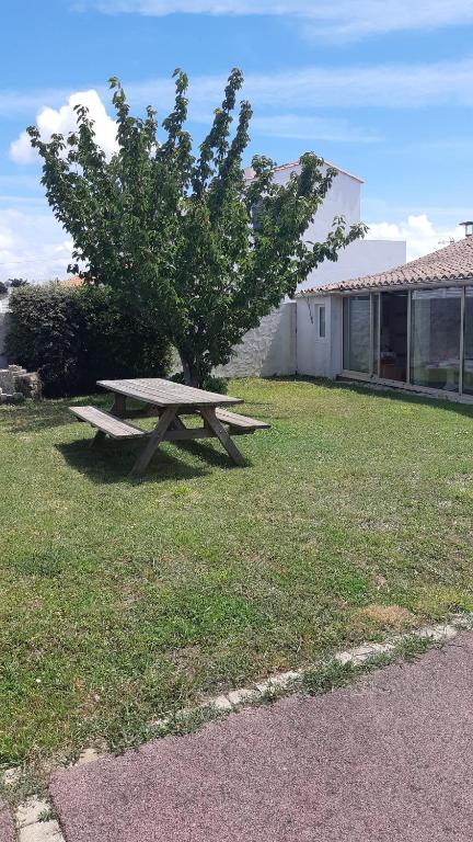 een picknicktafel in het gras naast een boom bij Maison de la mer in Brétignolles-sur-Mer