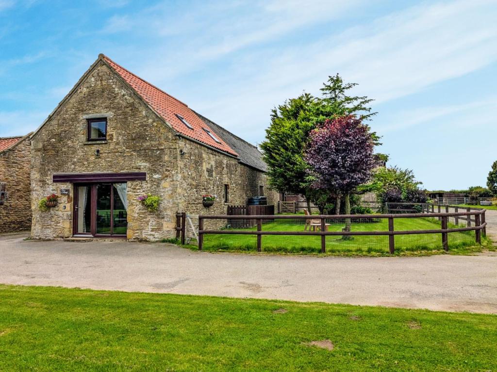 an old stone barn with a fence around it at May Cottage in Hackness