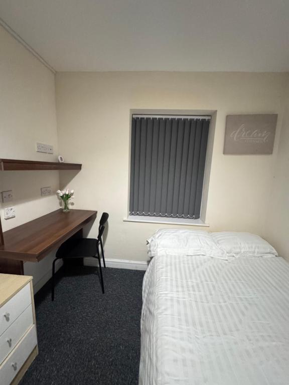 a bedroom with a bed and a desk and a window at Cozy modern 2 bedroom apartment with comfortable lounge in Preston