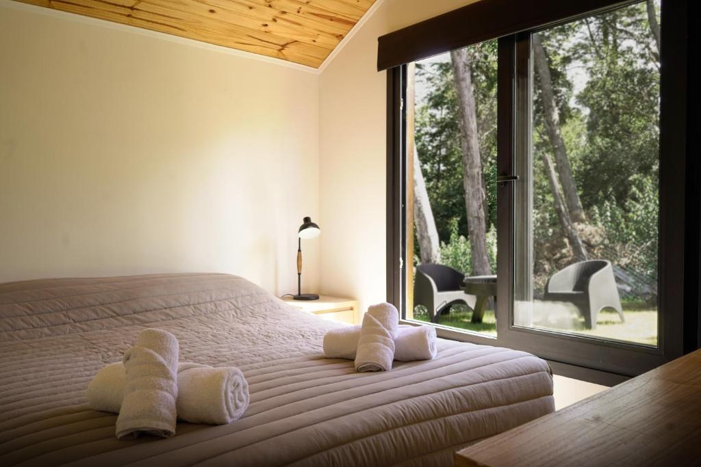 Un dormitorio con una cama con almohadas blancas y una ventana en Henko 2, en Villa La Angostura