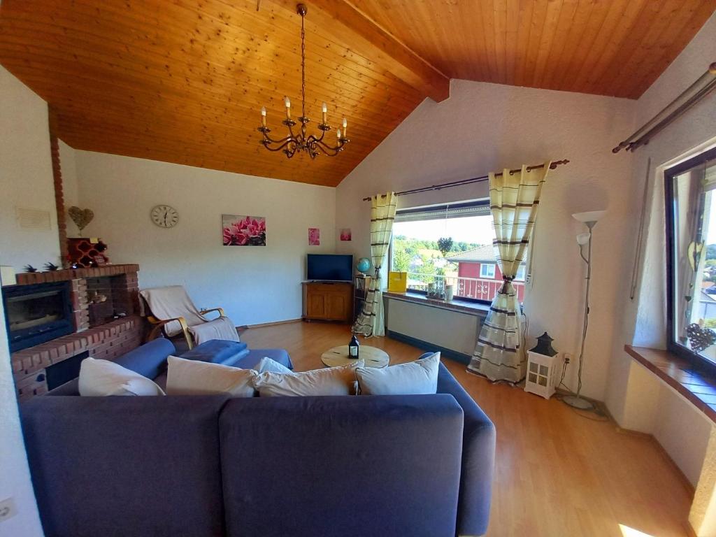un soggiorno con divano blu e lampadario pendente di Eifel Urlaub mit Hunden Ferienhaus Schwalbennest Schalkenmehren a Schalkenmehren