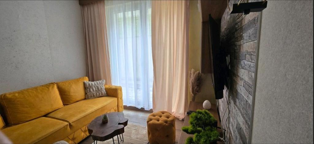 a living room with a yellow couch and a window at Magic Apartman Kop - Kraljevi Cardaci in Kopaonik