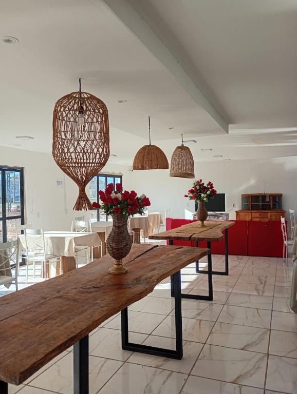 a dining room with a wooden table with flowers on it at Hotel Villa De Carli Santa Terra in Bagé
