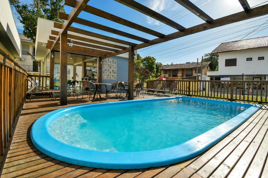 a large blue pool on a deck with a pergola at Mar de Bombinhas - Centro in Bombinhas