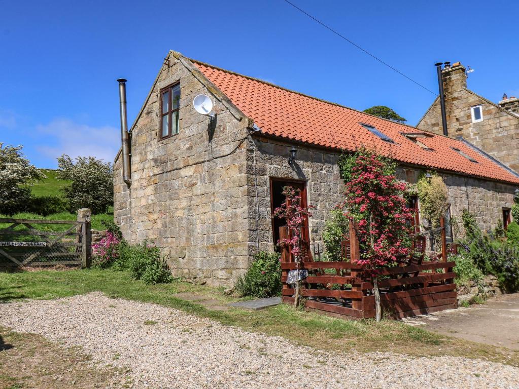 an old stone building with a red roof at Wildflower Cottage in Lealholm
