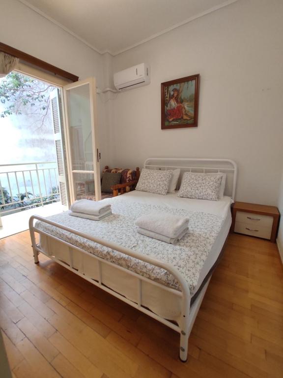 a white bed in a room with a large window at Hellen Guest House in Mesochórion