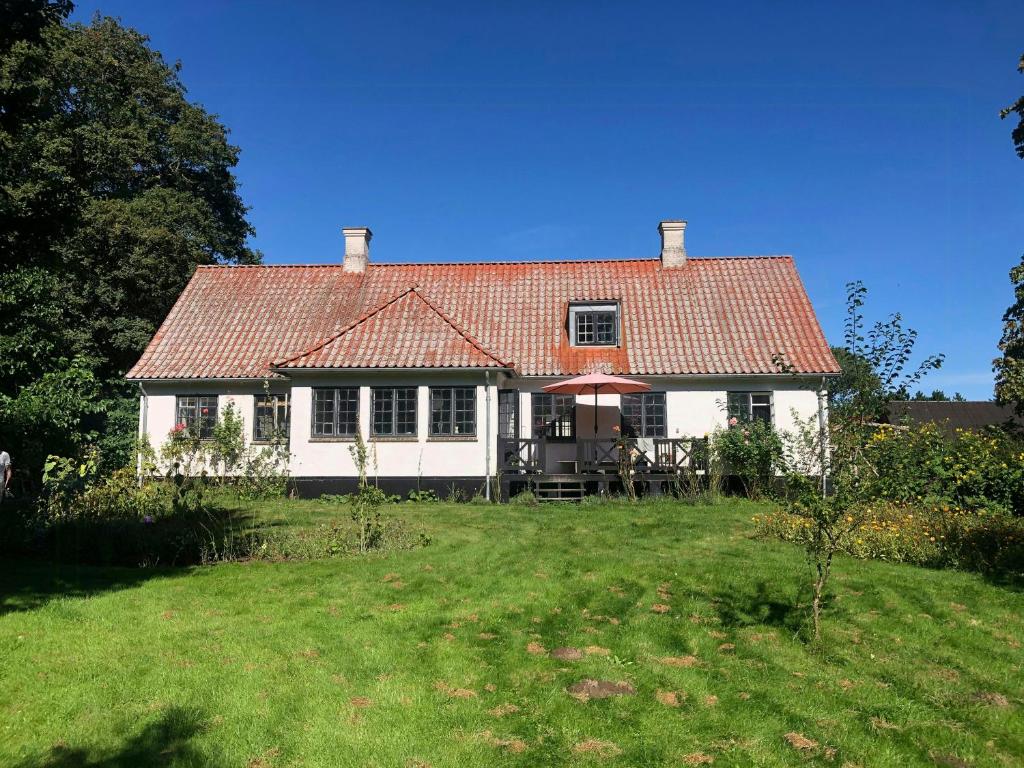 a white house with a red roof on a yard at Forest Ranger's House With Sea View In Kalvehave in Kalvehave