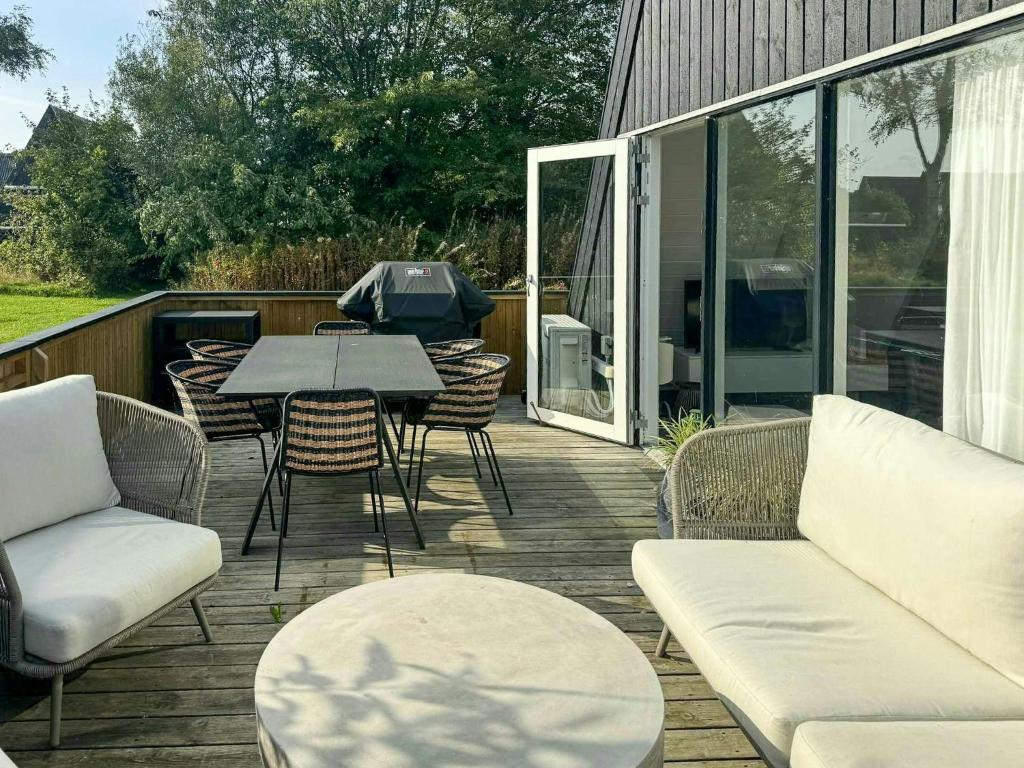 une terrasse en bois avec une table, des chaises, une table et des chaises dans l'établissement Holiday Home At Himmerland Golf & Spa Resort, à Gatten