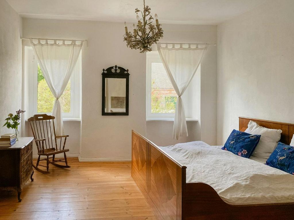 a bedroom with a bed and a chair and windows at Historic Manor House In Stettiner Haff Nature Park in Neuensund