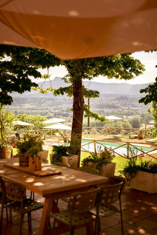 a wooden table with chairs and a view of a tree at Stone Villa With Panoramic Pool in Poppi