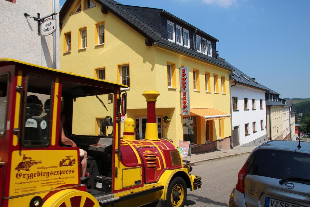 un pequeño vagón de tren estacionado frente a un edificio amarillo en Apartments Sport Fudel, en Kurort Oberwiesenthal