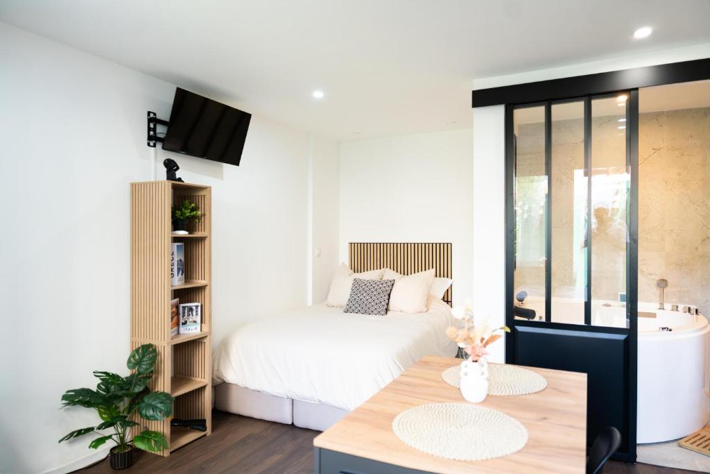 a white bedroom with a bed and a table at Douceur de Soie - Private Spa in Fresnes