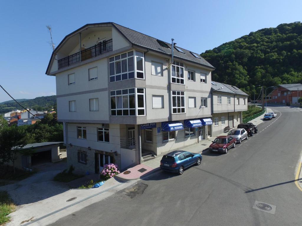 a large white building with cars parked in front of it at Casa Poy in Becerreá