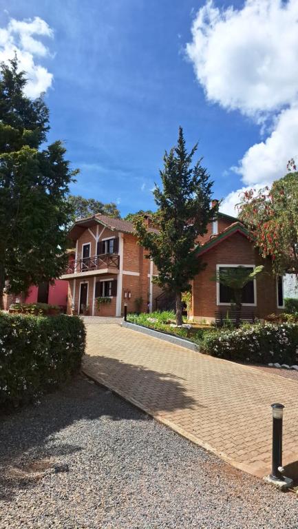 a house with a brick driveway in front of it at Pousada Encanto da Serra in Monte Verde