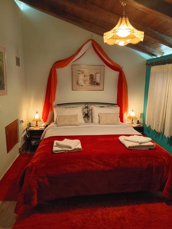 a bedroom with a large bed with a red blanket at Eleni Country Cottage 2 in Feneos