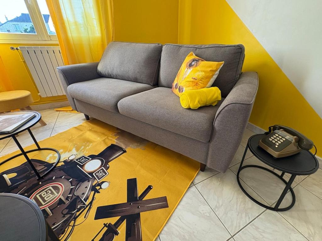a living room with a gray couch with a yellow pillow at Chez Micheline et Gilbert in Villebernier