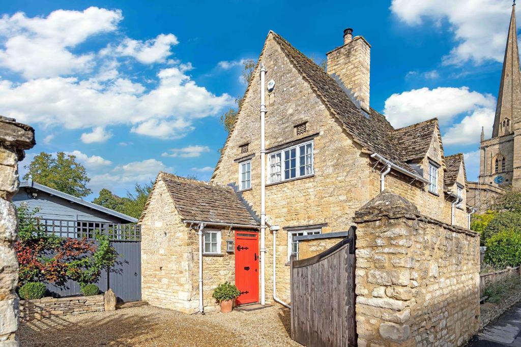 an old stone house with a red door at Church Cottage in Burford