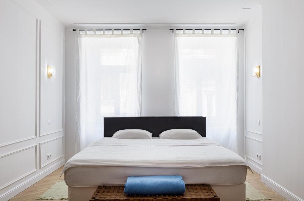 Cama en habitación con paredes y ventanas blancas en Feel Lviv! Old City Apartment, en Leópolis