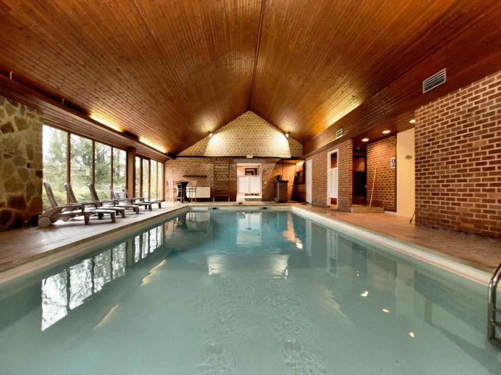 a large swimming pool with a wooden ceiling at Durbuy Forest Villa with Pool in Grandhan