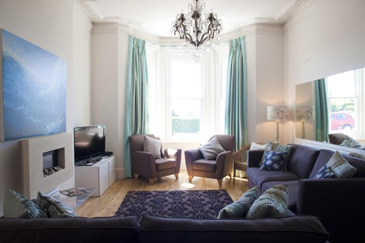 uma sala de estar com um sofá e cadeiras e uma televisão em Villa Lavinia em Ventnor