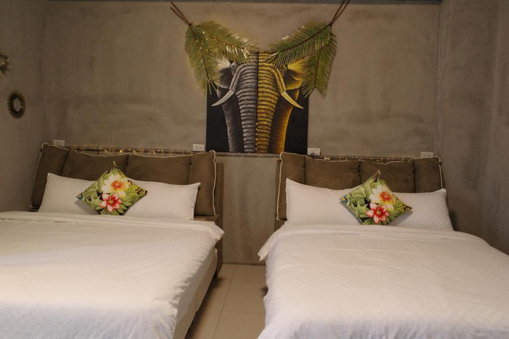 zwei Betten in einem Zimmer mit einer Palme im Hintergrund in der Unterkunft Lost in Memory in Sanxing Township