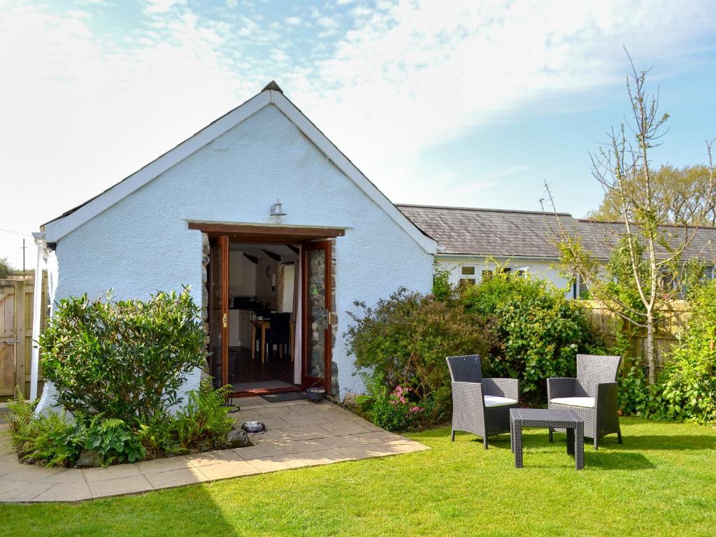 a white house with chairs and a table in the yard at Sunrise in St Austell