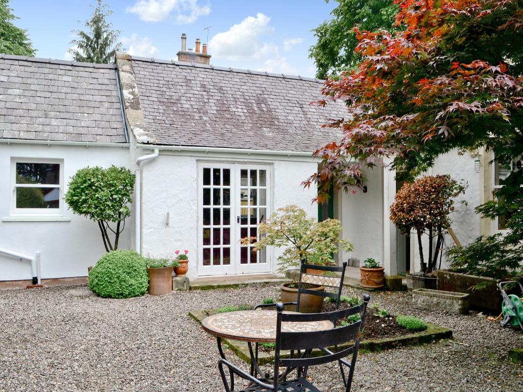 a white house with a table and chairs in front of it at Roseburn Cottage in Moffat