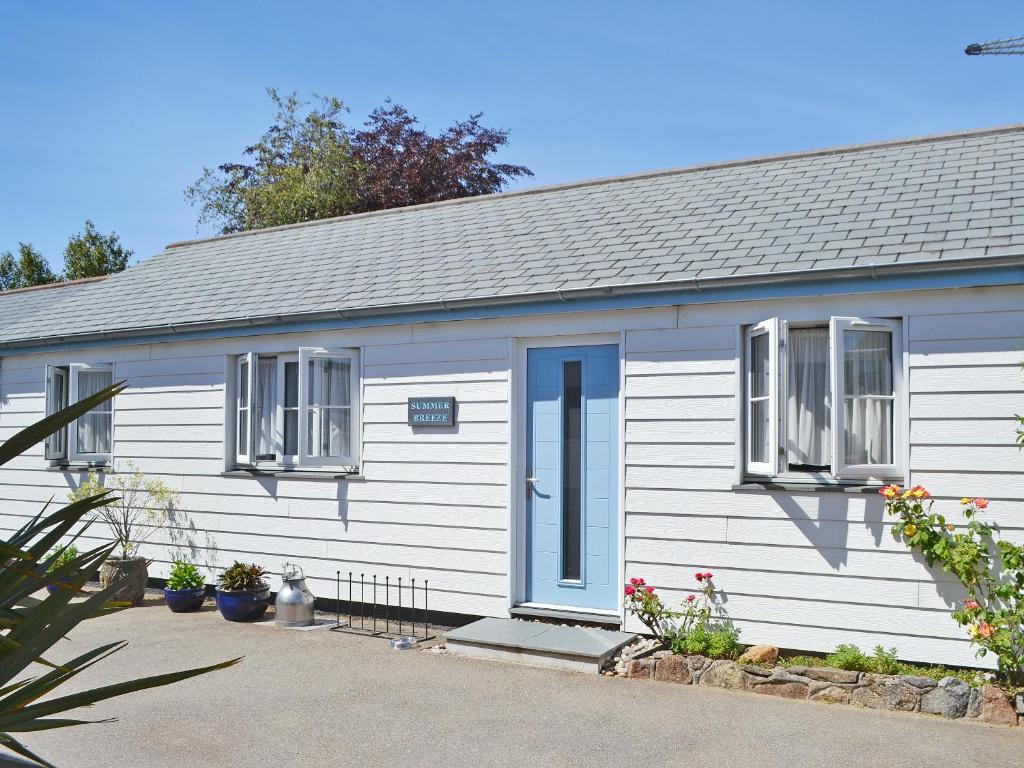 a white building with a blue door and windows at Summer Breeze in St Austell