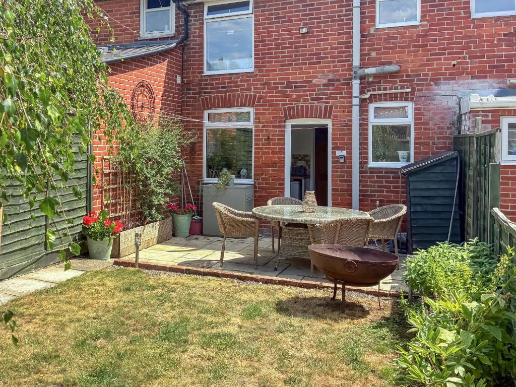 a patio with a table and chairs in front of a brick building at Willow Cottage in Stockbridge