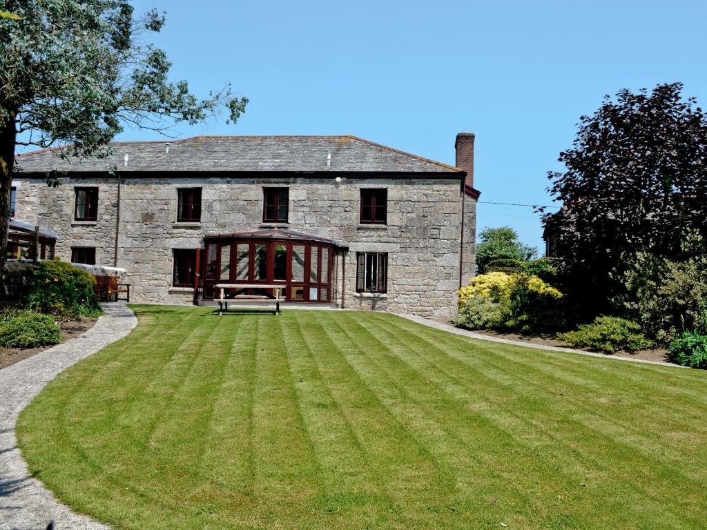 an old stone house with a large lawn at Prideaux Farmhouse in Luxulyan